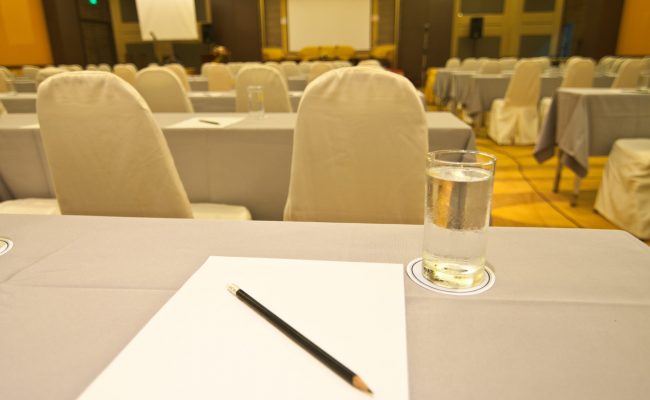 White paper with pencil and glasses on table in meeting room